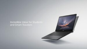 An ASUS L210 laptop open at a 180-degree lay-flat angle on a colorful patterned student desk, next to a notebook.